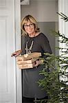 Sweden, Smiling senior woman entering room holding Christmas presents