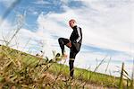 Sweden, Halland, Steninge, Mid-adult man stretching in field