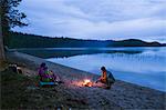 Sweden, Vasterbotten, Vindeln, Skatan, Parents with girls (2-3, 8-9) enjoying campfire by lake