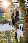 Sweden, Sodermanland, Alvsjo, Woman sawing fir tree on backyard