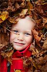 Sweden, Portrait of girl (2-3) buried in autumn leaves