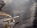 Sweden, Vastergotland, Lerum, Lake Aspen, Boy (10-11) standing on springboard projecting off rocky lakeshore