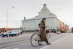 Sweden, Uppland, Stockholm, Vasatan, Sankt Eriksgatan, Woman cycling on city street