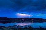 Sweden, Uppland, Stockholm Archipelago, Vettershaga, Lightning above lake at dusk