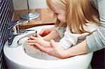 Side view of mother helping daughter (2-3) in washing hands