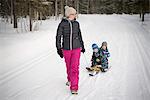 Finland, Lapland, Levi, Mom pulling sons (2-3, 4-5) on sled