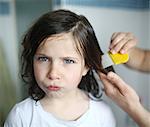 A mother passes a lice comb in the hair of her 6 years old girl