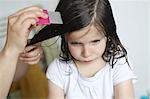 A mother passes a lice comb in the hair of her 6 years old girl