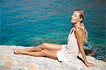 Young woman relaxing in the sun on a wall