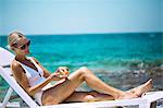 Young woman applying sun cream on a lounger