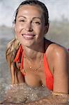 Close-up of smiling blond woman lying in water