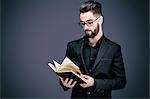 Portrait of a young man in a suit reading a book