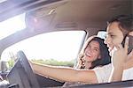 Couple riding in car together while driver chats on cell phone without hands-free device