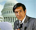 1970s NEWS REPORTER BLACK HAIR SPORT JACKET SPEAKING INTO MICROPHONE LOOKING AT CAMERA CAPITOL WASHINGTON DC USA