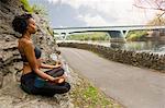 Woman sitting cross legged on rock meditating