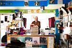 Portrait of mature man in record shop, leaning on stack of records