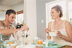 Young couple eating breakfast cereal at kitchen table