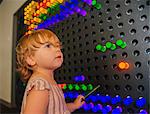 Female toddler mesmerized by colorful illuminated panel