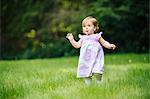 Female toddler running in park grass