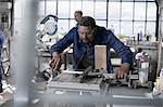 Carpenter using machine to measure wood in workshop