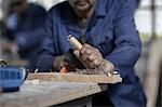 Hands of carpenter using chisel on wood in workshop