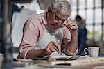 Senior carpenter using calculator in wood workshop