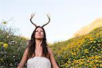 Woman putting on horns in field of wildflowers