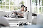 Woman reading on sofa with pet dogs