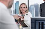 Businessman handing over document to businesswoman at work desk