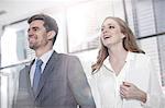 Businessman with businesswoman carrying digital tablet outside office building