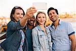 Adult friends taking smartphone selfie on pier, Santa Monica, California, USA