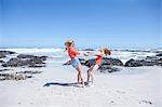 Girl and young woman holding hands and spinning each other around on beach, Cape Town, South Africa