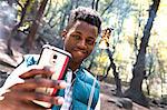 Young male hiker taking smartphone selfie with toasted marshmallow in forest, Arcadia, California, USA