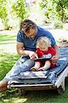 Sweden, Skane, Mossby, Daughter with father sitting on deckchair and using tablet pc