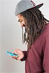 Studio shot of young man in dreadlocks using smartphone