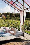 Sweden, Uppland, Solna, Ulriksdal, Woman sleeping on swing in Ulriksdals Handelstradgard