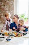 Sweden, Mother with two children (2-3, 10-11) eating breakfast