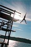 Sweden, Bohuslan, Fjallbacka, Silhouette of woman jumping off platform