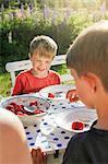 Sweden, Halsingland, Jarvso, Brothers (4-5, 6-7) eating strawberries in garden