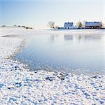 Sweden, Skane, Arrie, Lake and houses in winter