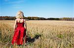 Sweden, Vastra Gotaland, Gullspang, Girl (4-5) wearing red dress standing in field