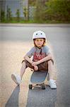 Sweden, Vastergotland, Lerum, Portrait of boy (8-9) sitting on skateboard on street