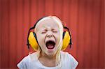 Sweden, Narke, Filipshyttan, Portrait of blonde girl (8-9) wearing ear muffs, screaming with eyes closed