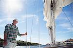 Sweden, West Coast, Bohuslan, Marstrand, Mature man standing on deck of sailboat