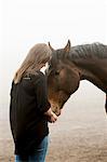 Sweden, Skane, Mid-adult woman feeding her horse