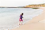 Portugal, Alentejo, Vila Nova de Milfontes, Girl (4-5) running in surf