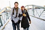 Sweden, Vasterbotten, Umea, Young couple walking on footbridge in winter