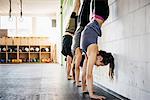 Germany, Young women and man practicing handstand in gym
