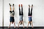 Germany, Young women and man practicing handstand in gym