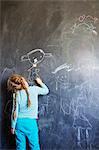 Finland, Girl (4-5) drawing on chalkboard